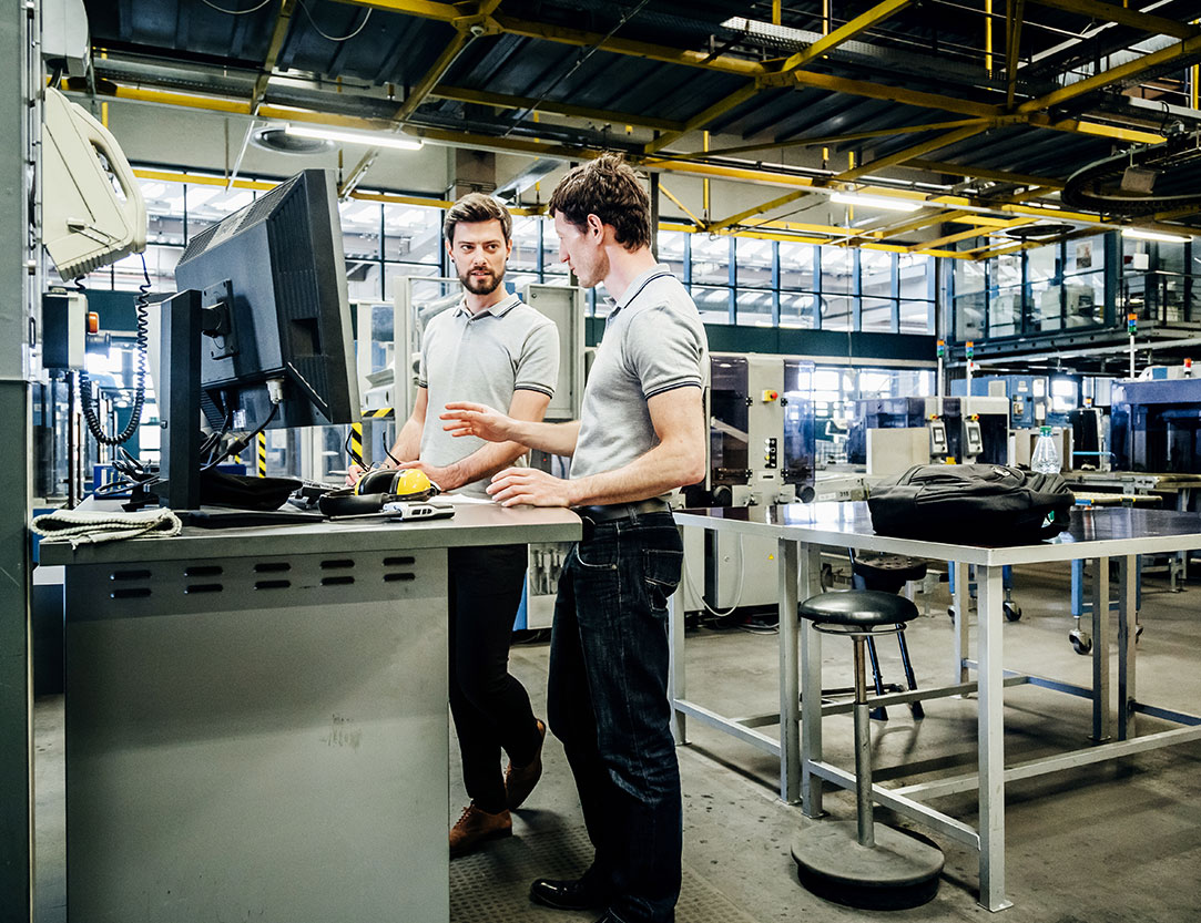 Zwei junge Männer die sich innerhaln einer Industriehalle unterhalten